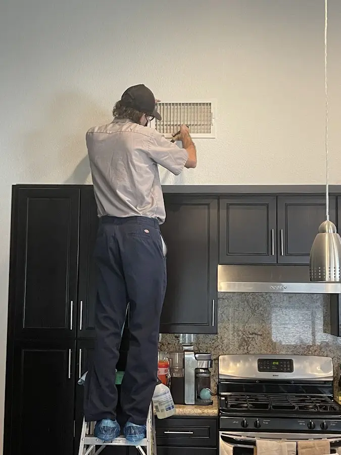 Technician inspecting an air vent during HVAC service in Demopolis